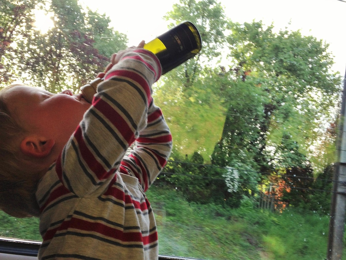 Baby playing with a small wine bottle on a train.