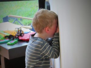 Toddler having a tantrum against a wall