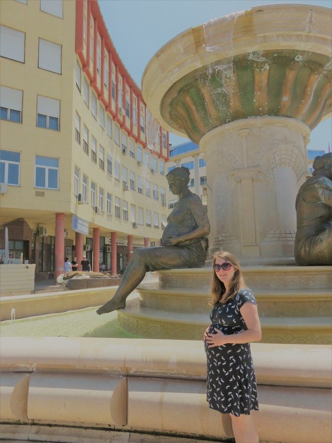 Pregnant woman copying pose of pregnant lady statue in Skopje, Macedonia