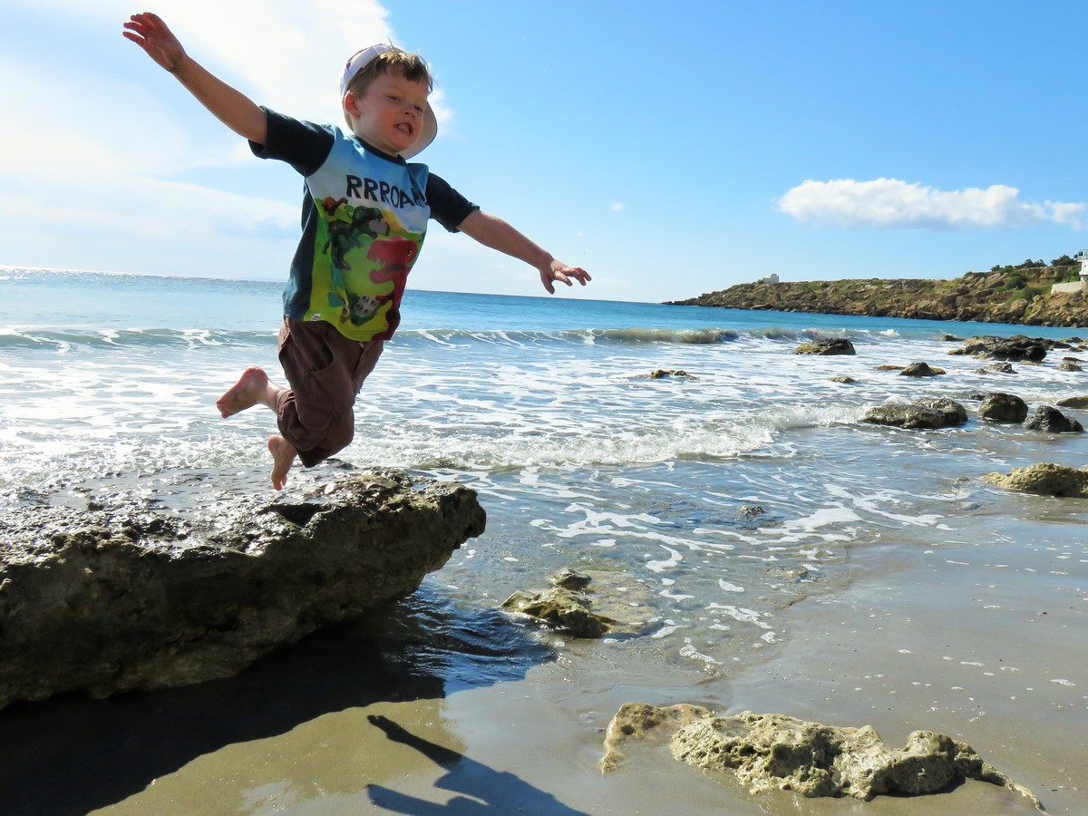 Toddler jumping off rock on beach in Frangokastello, Crete