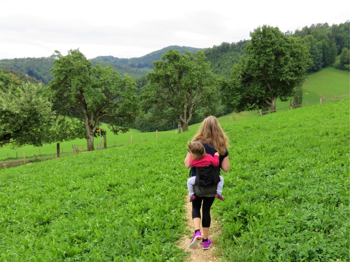Woman carrying toddler on hike in Switzerland.