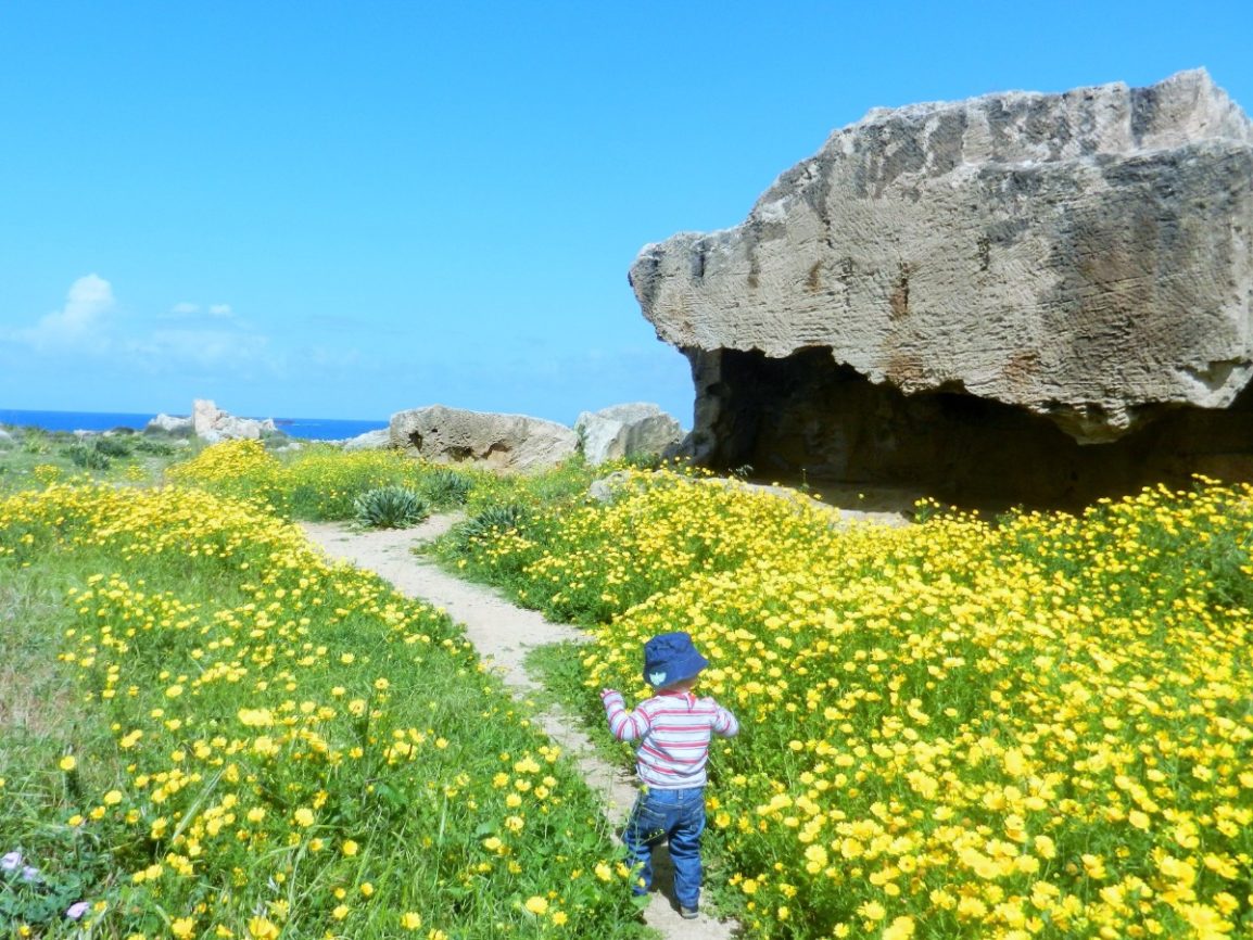 Toddler walking through a meadow at Tomb of the Kings, Cyprus
