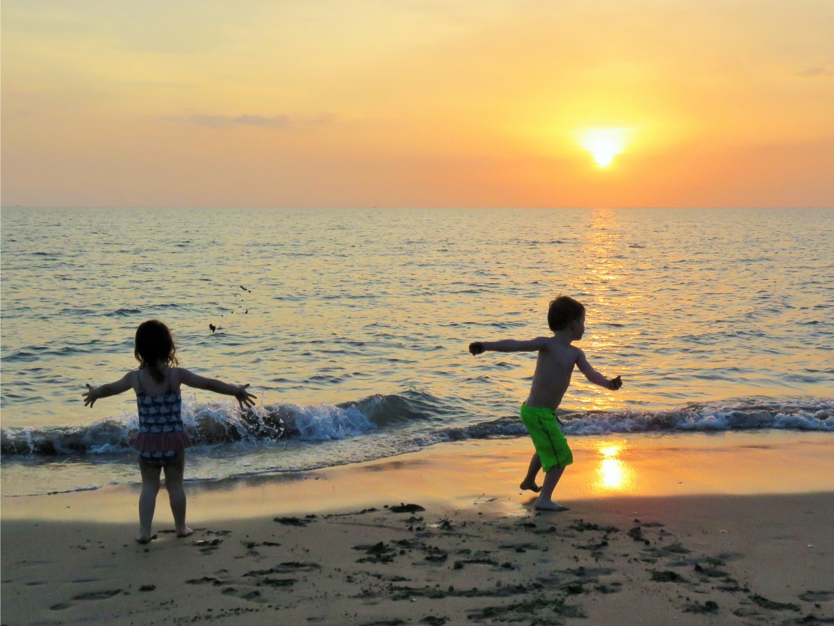 Girl and boy enjoying sunset on Ko Lanta, Thailand