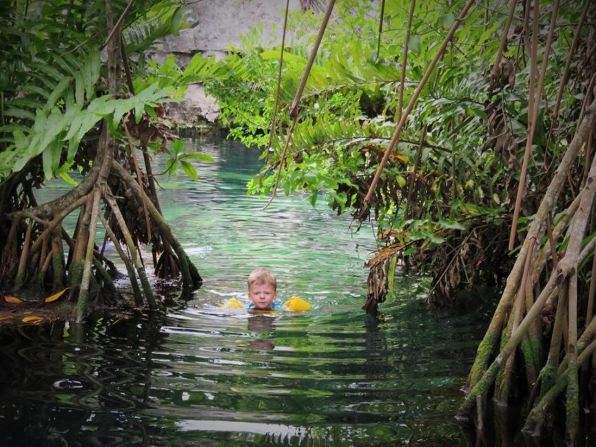 Boy swimming through mangroves in Puddler Jumper buoyancy vest.