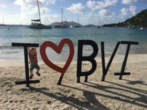 toddler swinging on I love BVI sign on beach