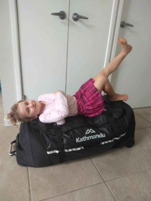 girl on luggage family packing tips