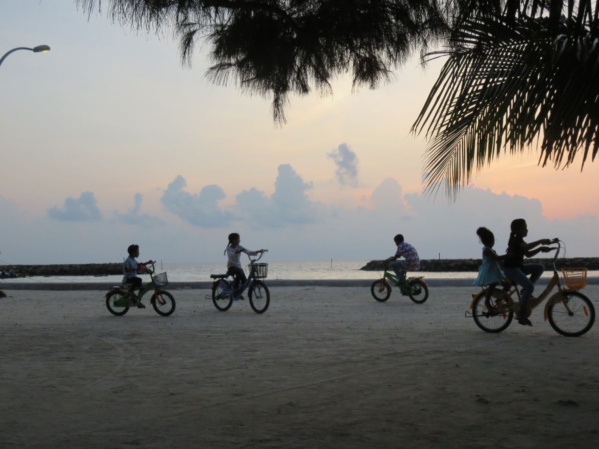 kids riding bikes on Gulhi Island at sunset