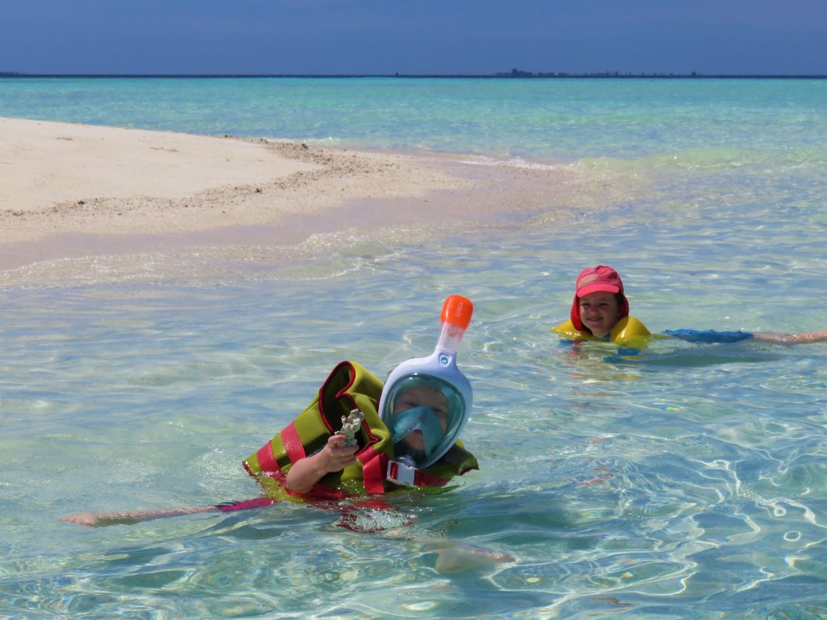 boy wearing snorkelling mask and girl in sea in the Maldives