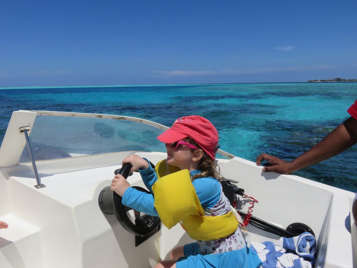 little girl driving a speedboat in the maldives