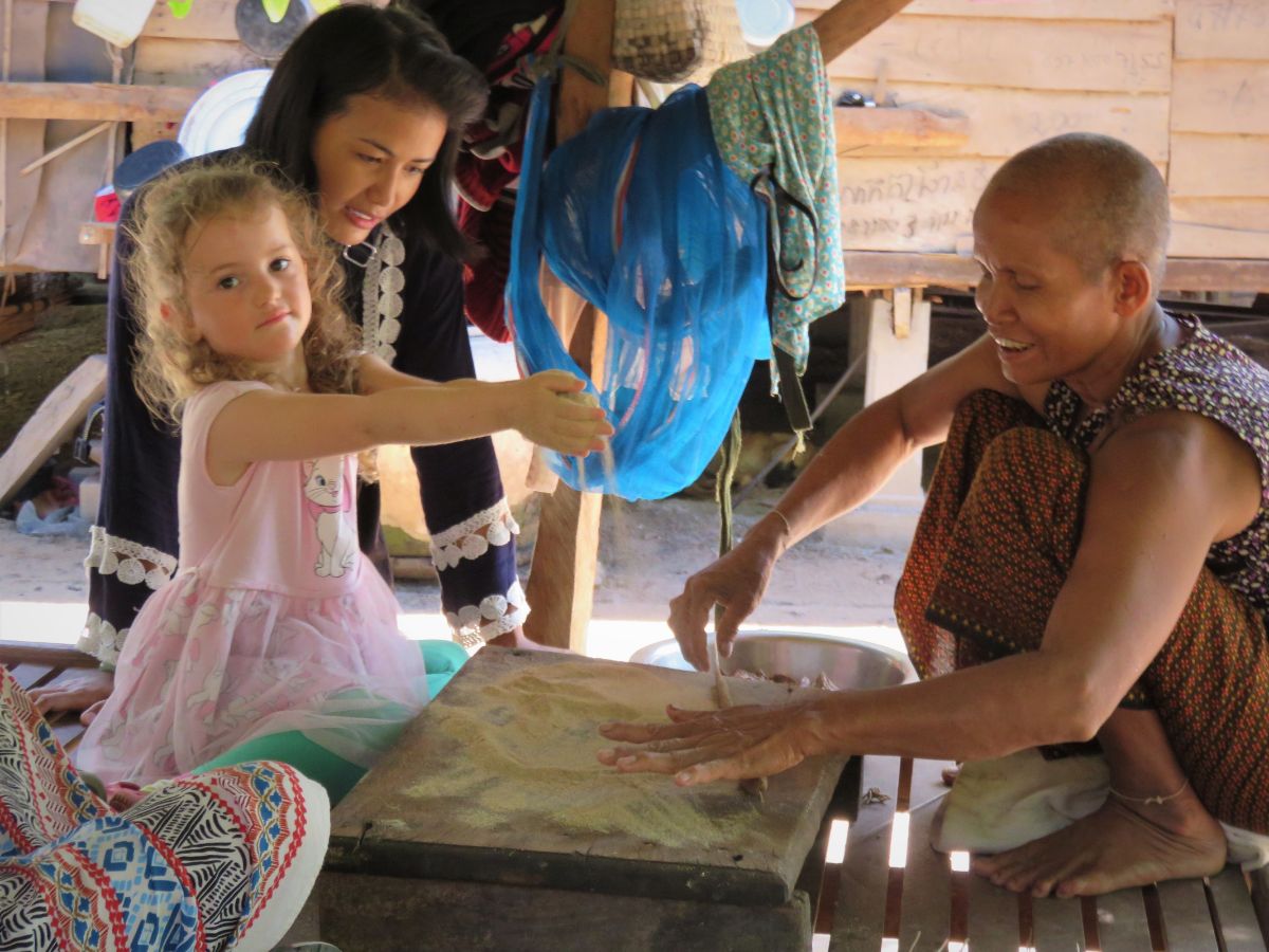 little girl making incense sticks in cambodia with local women