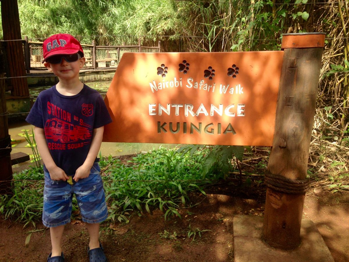 little boy standing by sign in Nairobi Kenya