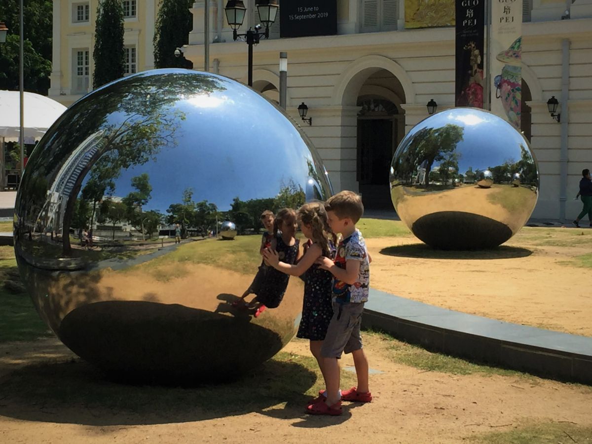 children in singapore playing at giant ball sculpture
