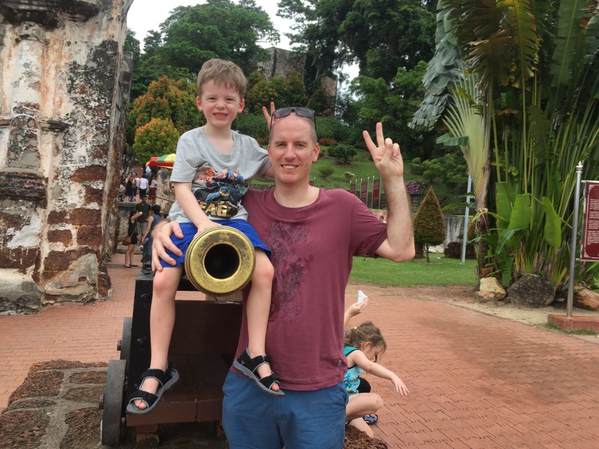 boy sitting on cannon in Melaka with his dad