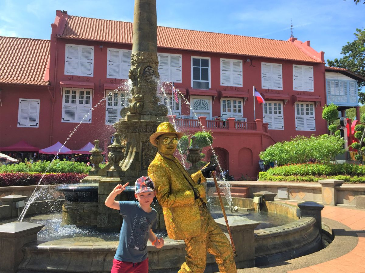 boy and golden man posing outside Stadhuys in Melaka