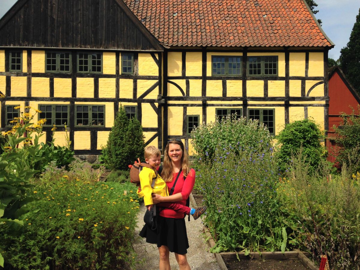 toddler and mother outside a yellow timber-framed building in Den Gamle By in Aarhus, Denmark