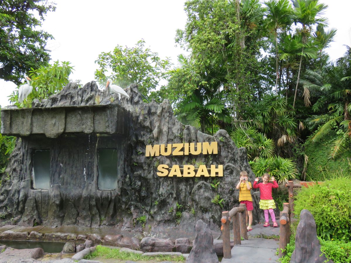 Muzium Sabah entrance sign with two children posing 